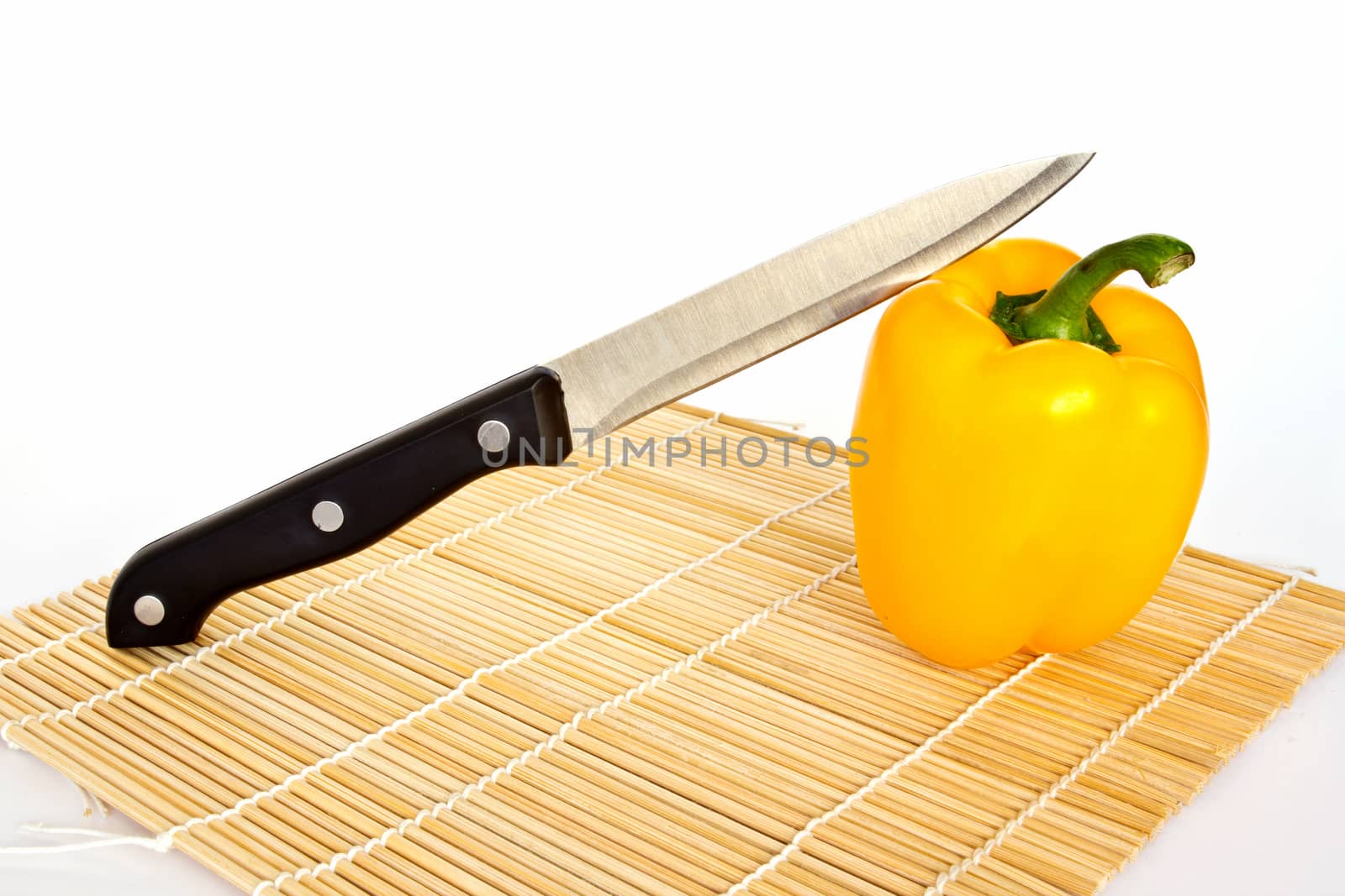 A knife on yellow sweet peppers isolated on a white background 