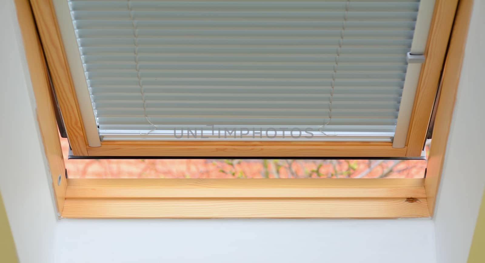 New opened wooden roof window with aluminous jalousie.