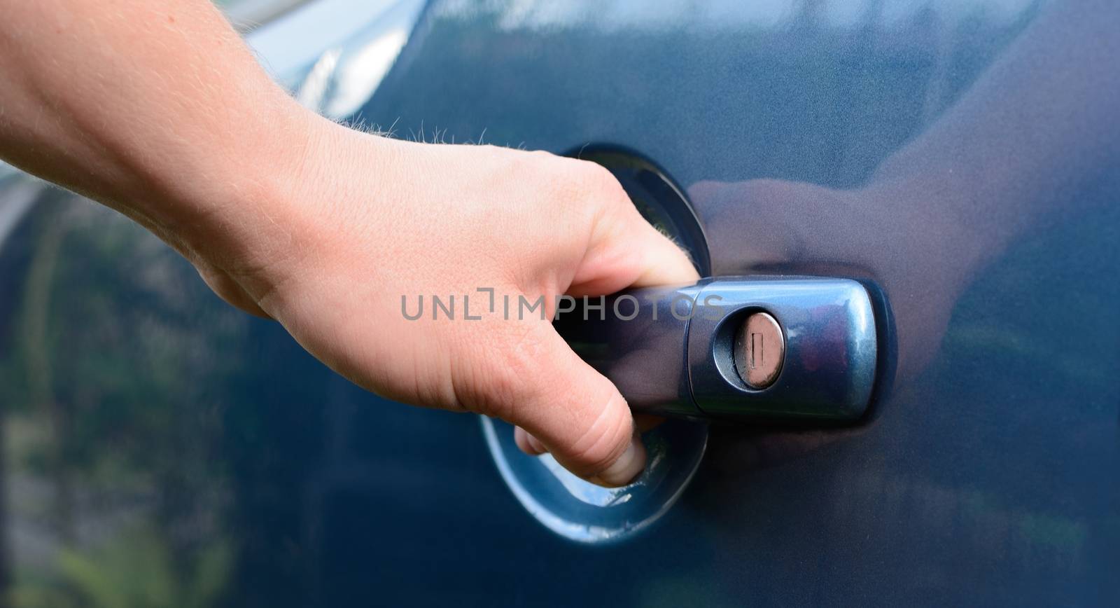 Mans hand holding the handle and opening blue car door. 