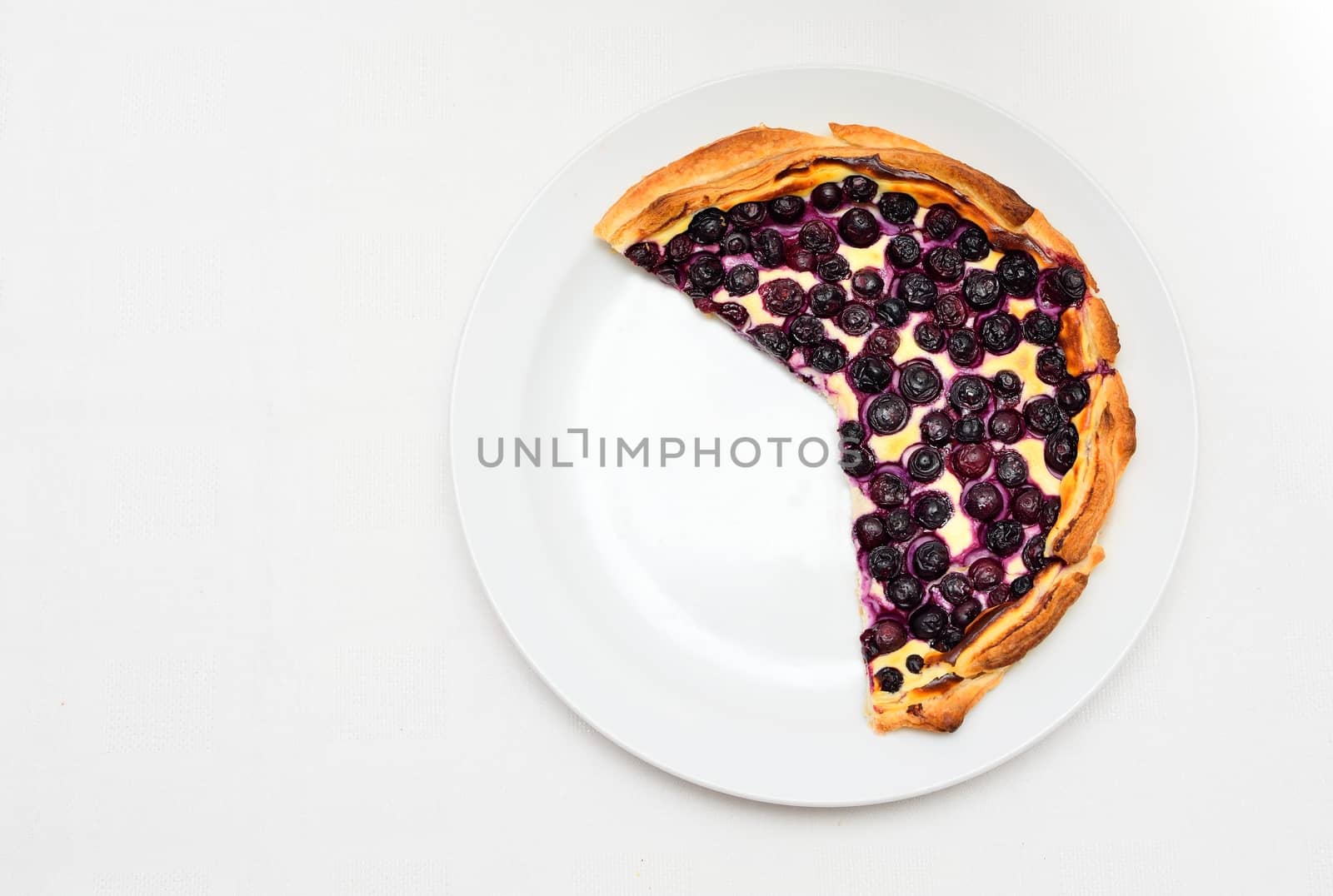 Top view on a blueberry cheese pie on the white plate.