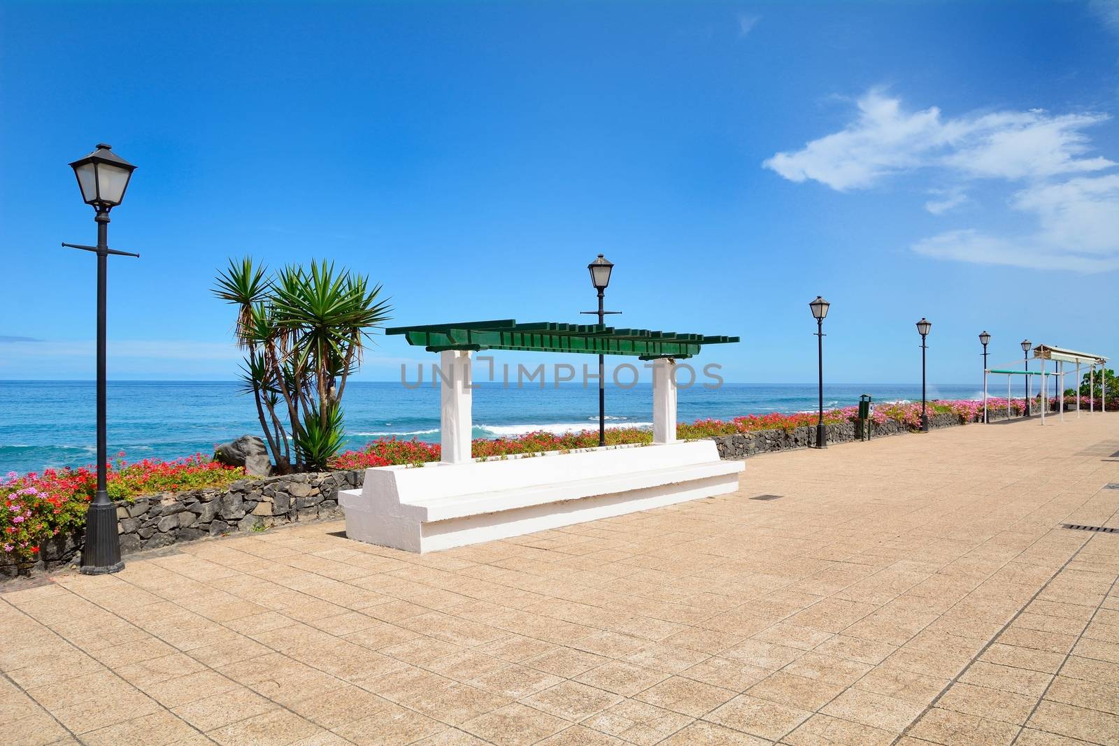 Ocean Promenade in Puerto de la Cruz, Tenerife, Spain with lamps and resting bench.