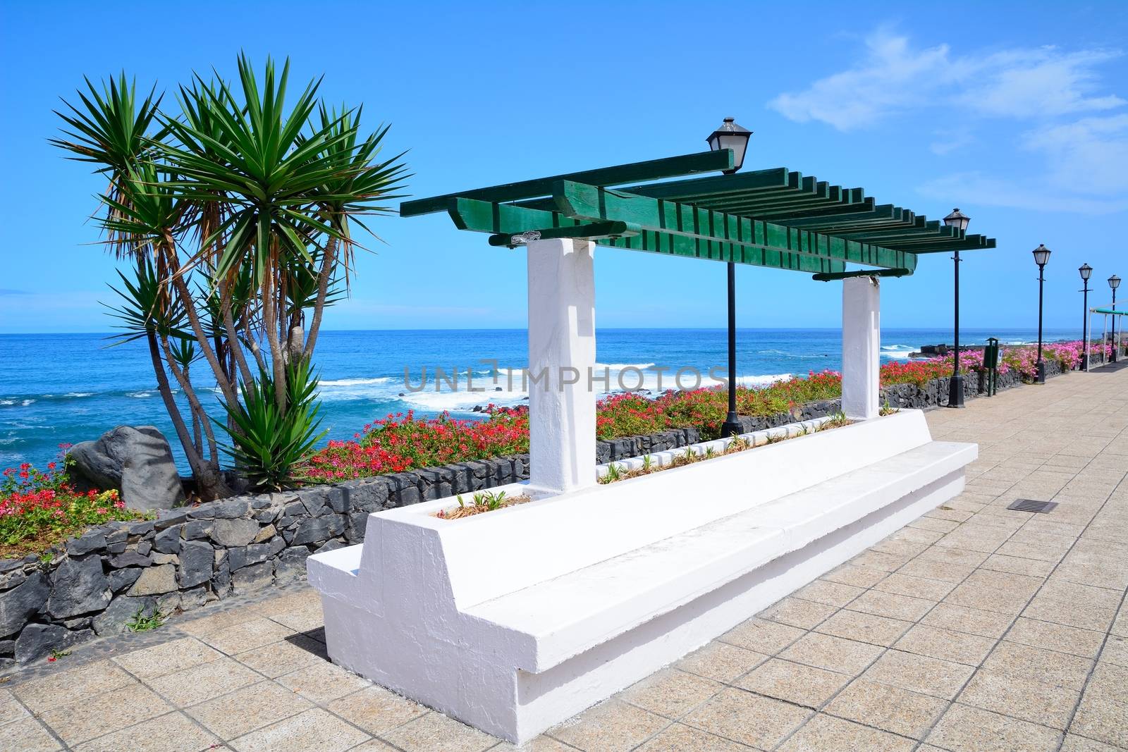 Ocean Promenade in Puerto de la Cruz, Tenerife, Spain with lamps and resting bench.