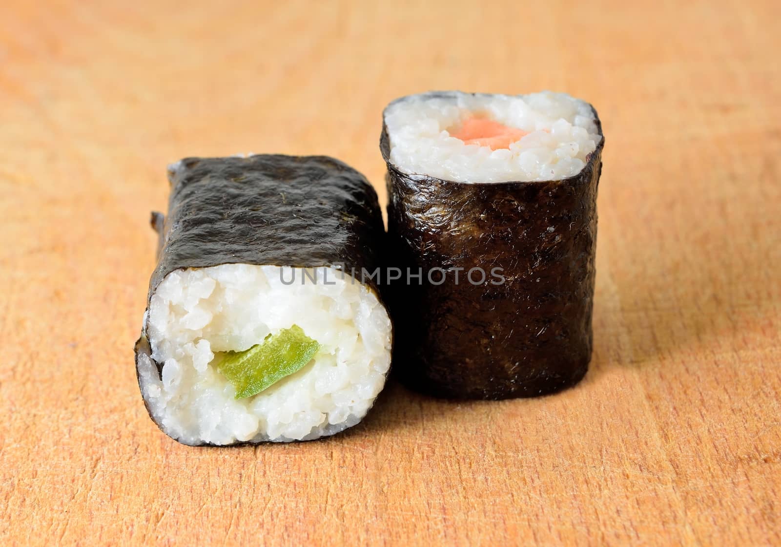 Sushi Hosomaki with salmon and green pepper on a wooden plate.