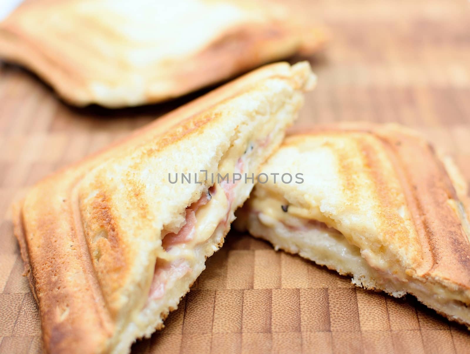 Baked toast with ham and cheese on a wooden plate.