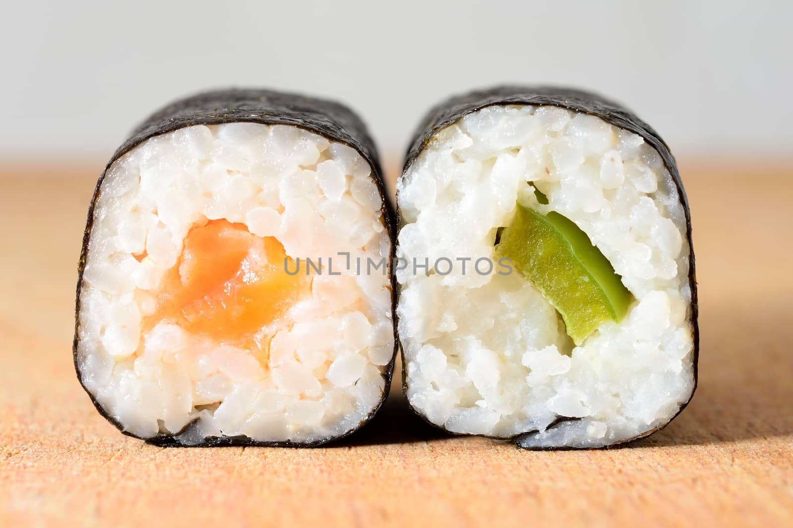 Sushi Hosomaki with salmon and green pepper on a wooden plate.