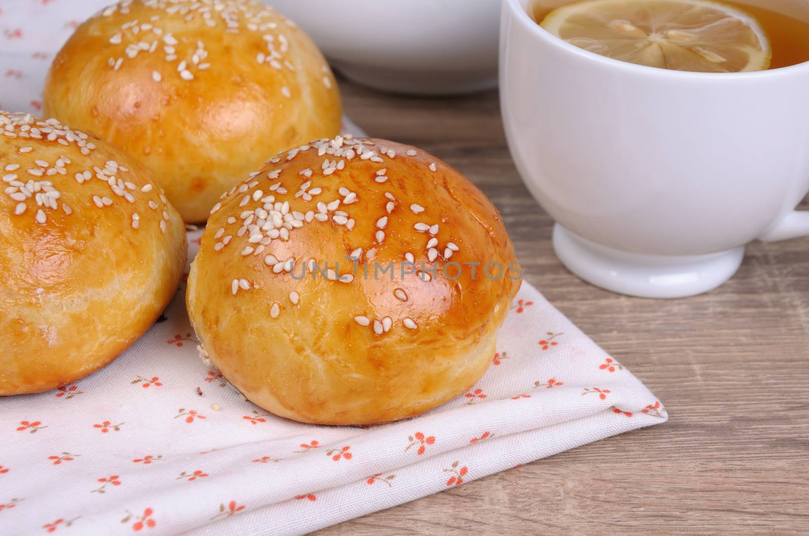 Buns with sesame seeds on a table and a cup of tea