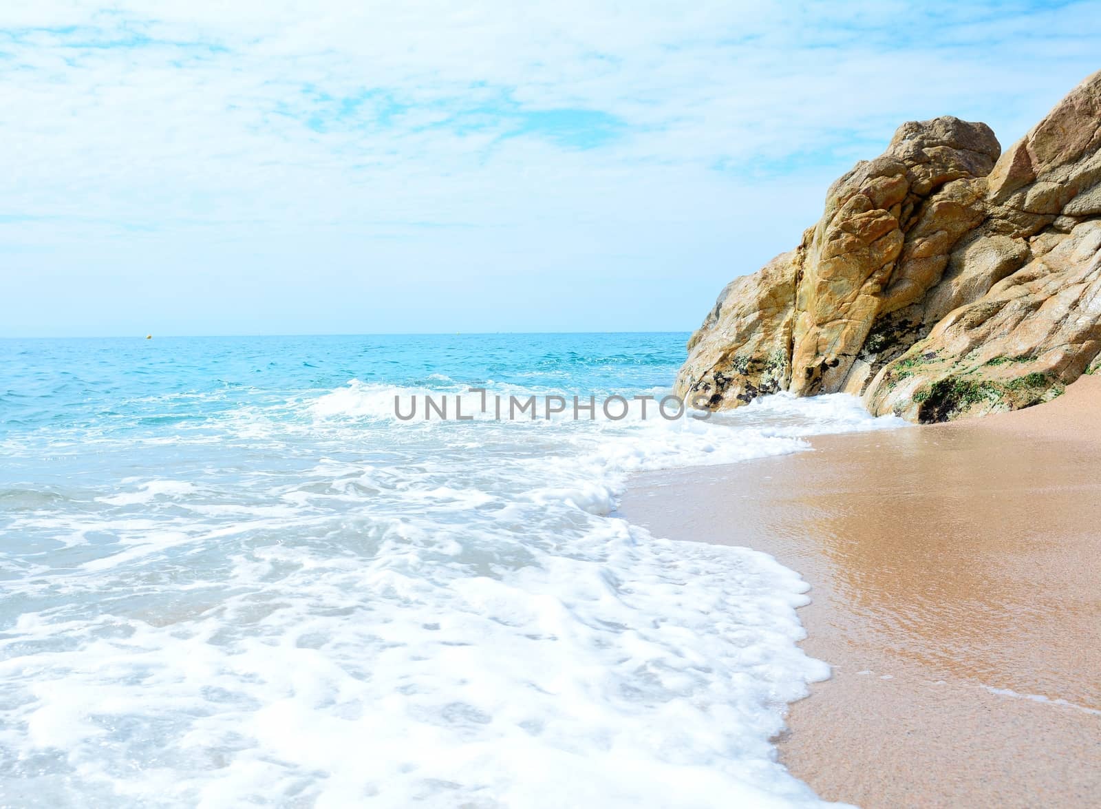 Beautiful beach with clear Mediterranean Sea and rock on the coast.