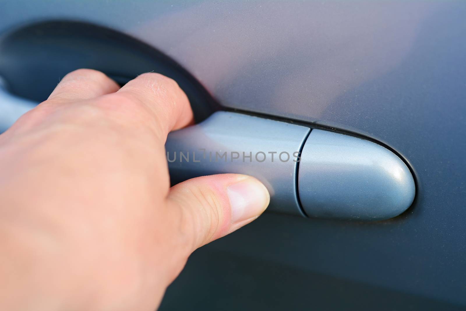 Mans hand holding the handle and opening blue car door.