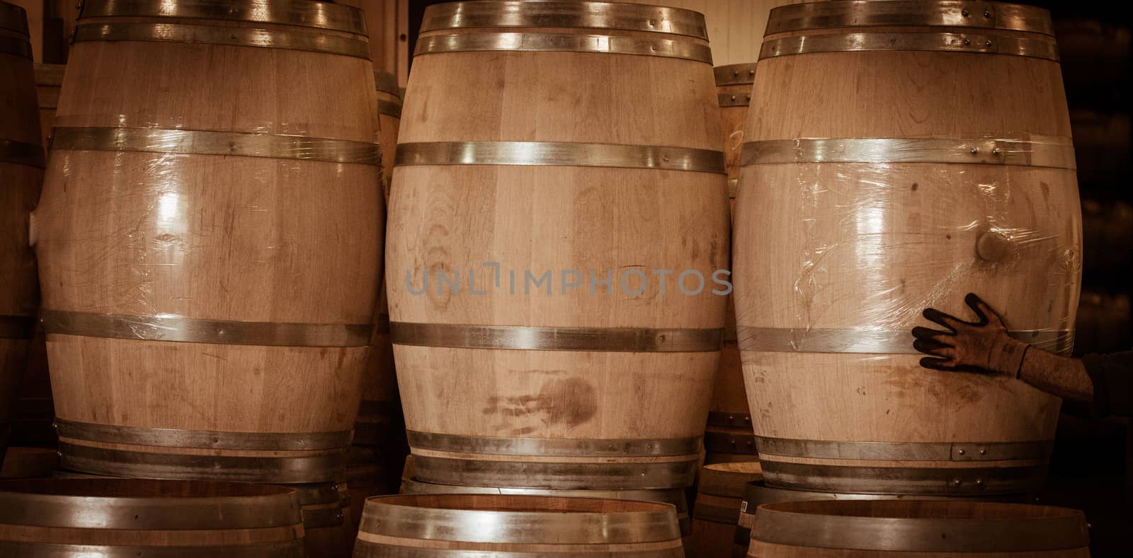 Winemaker barrels moving up or down by rolling on the ground in a large storage cellar, Bordeaux Vineyard, France