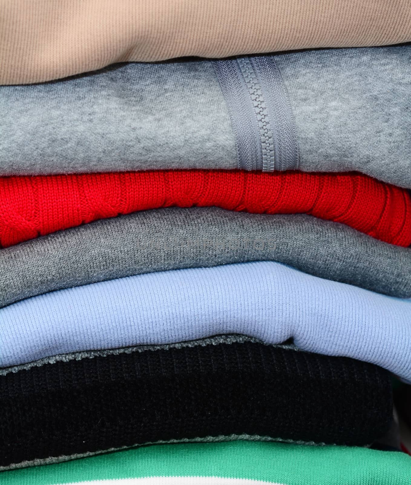 Stack of the multicolored falded clothes in the wardrobe.