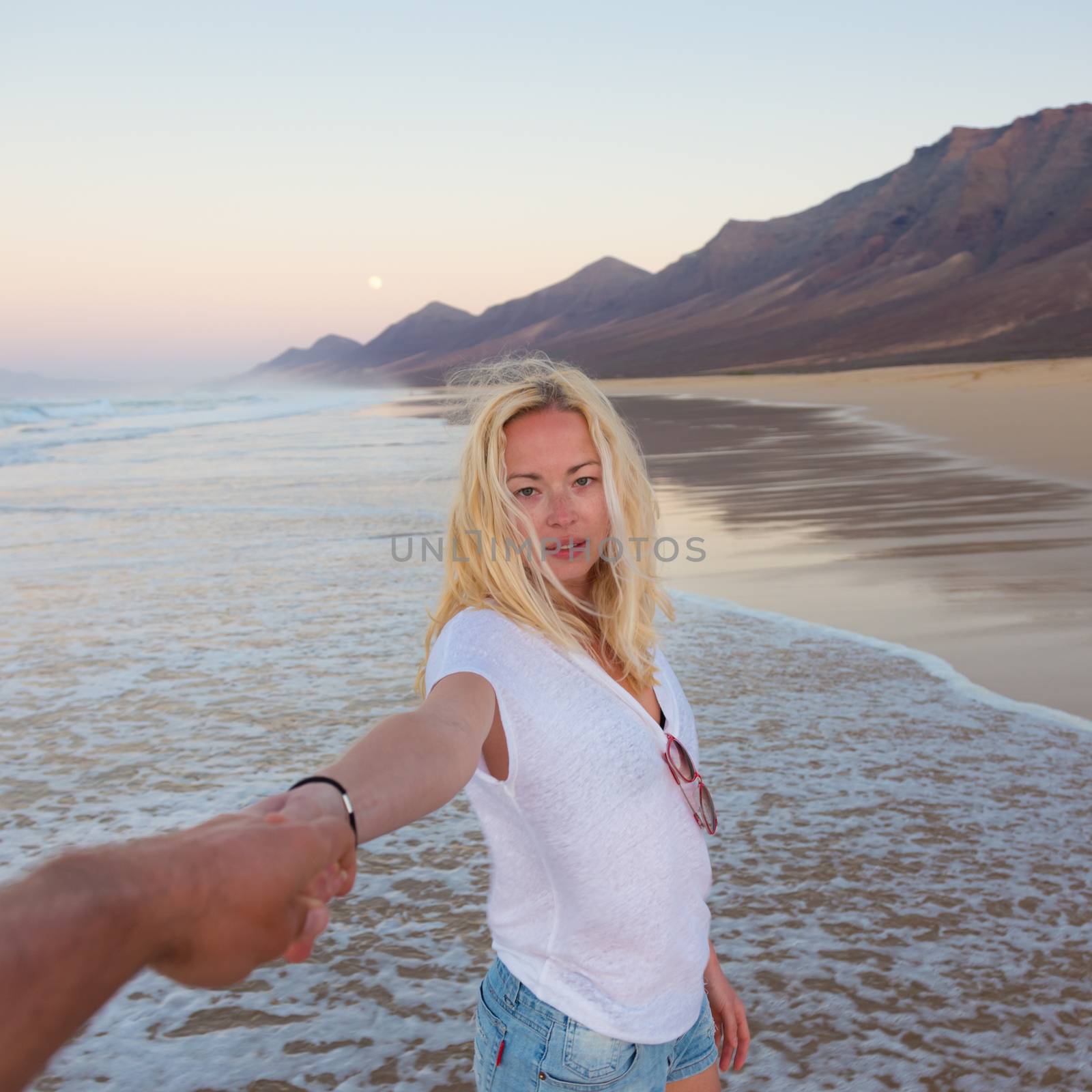 Romantic couple holding hands on beach. by kasto