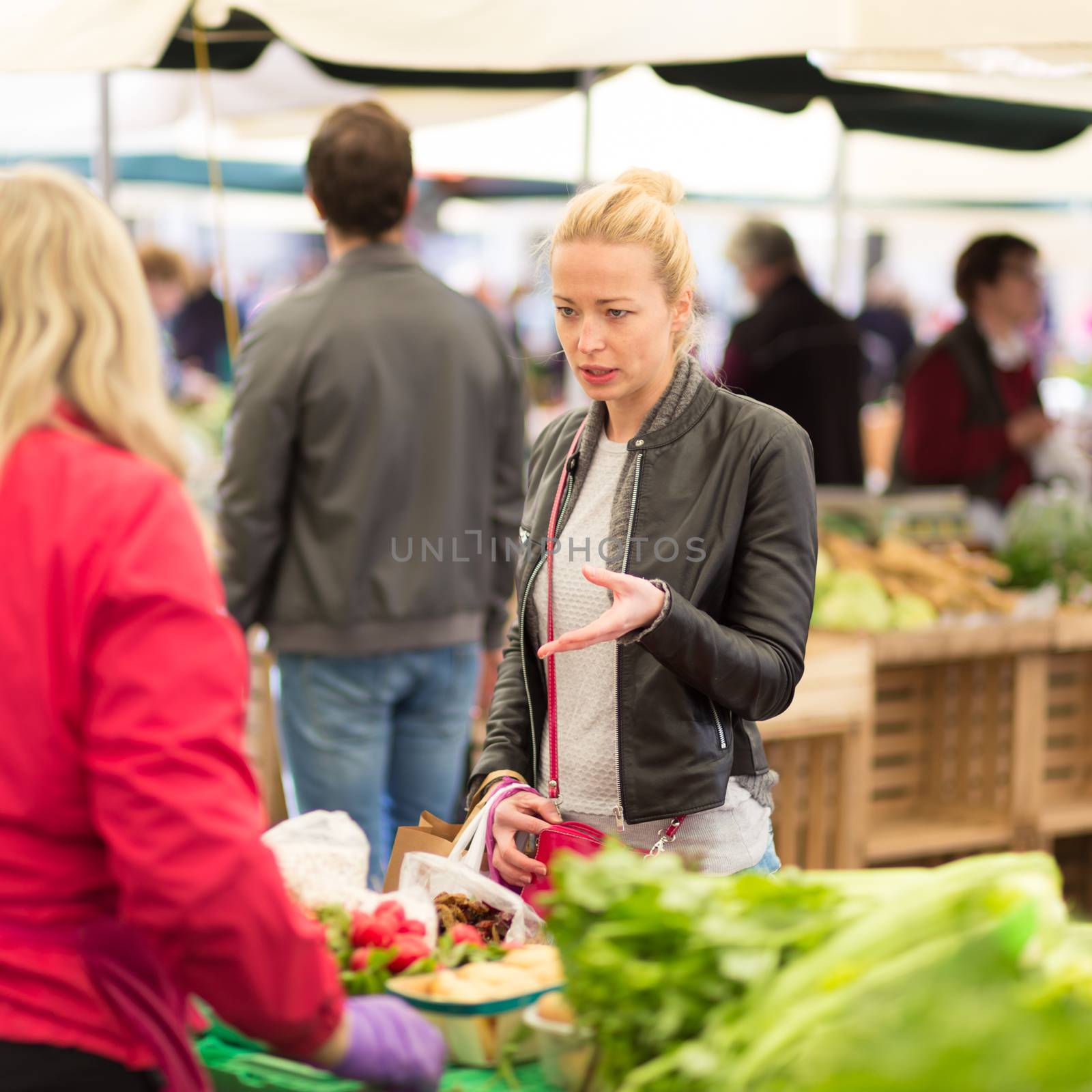 Woman buying fruits and vegetables at local food market. Market stall with variety of organic vegetable.