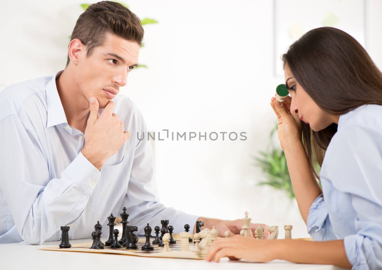 Young businessman and businesswoman playing chess in the office.