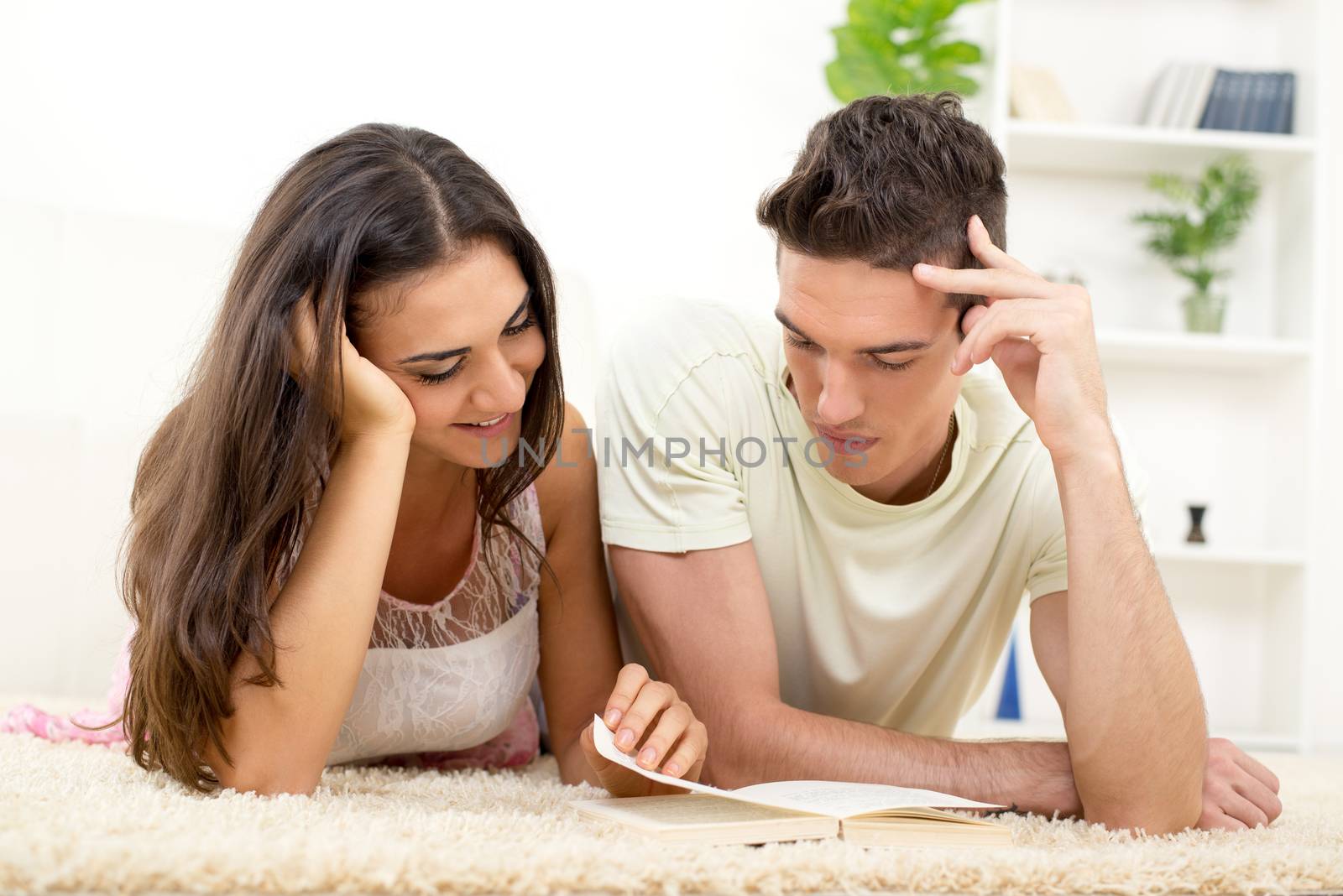 Happy couple at home reading book together on the carpet