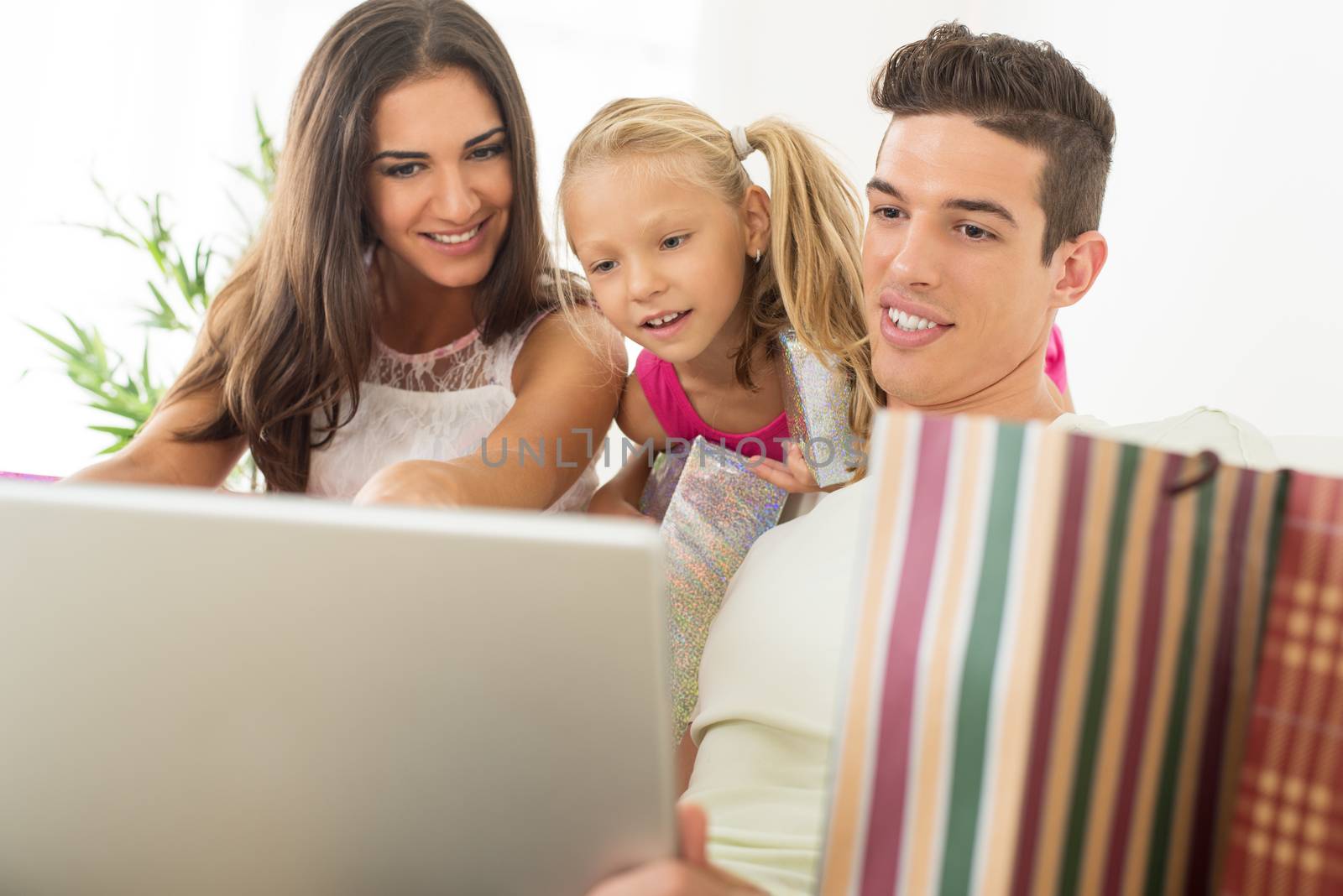 Beautiful happy family sitting at home with laptop and shopping bags.