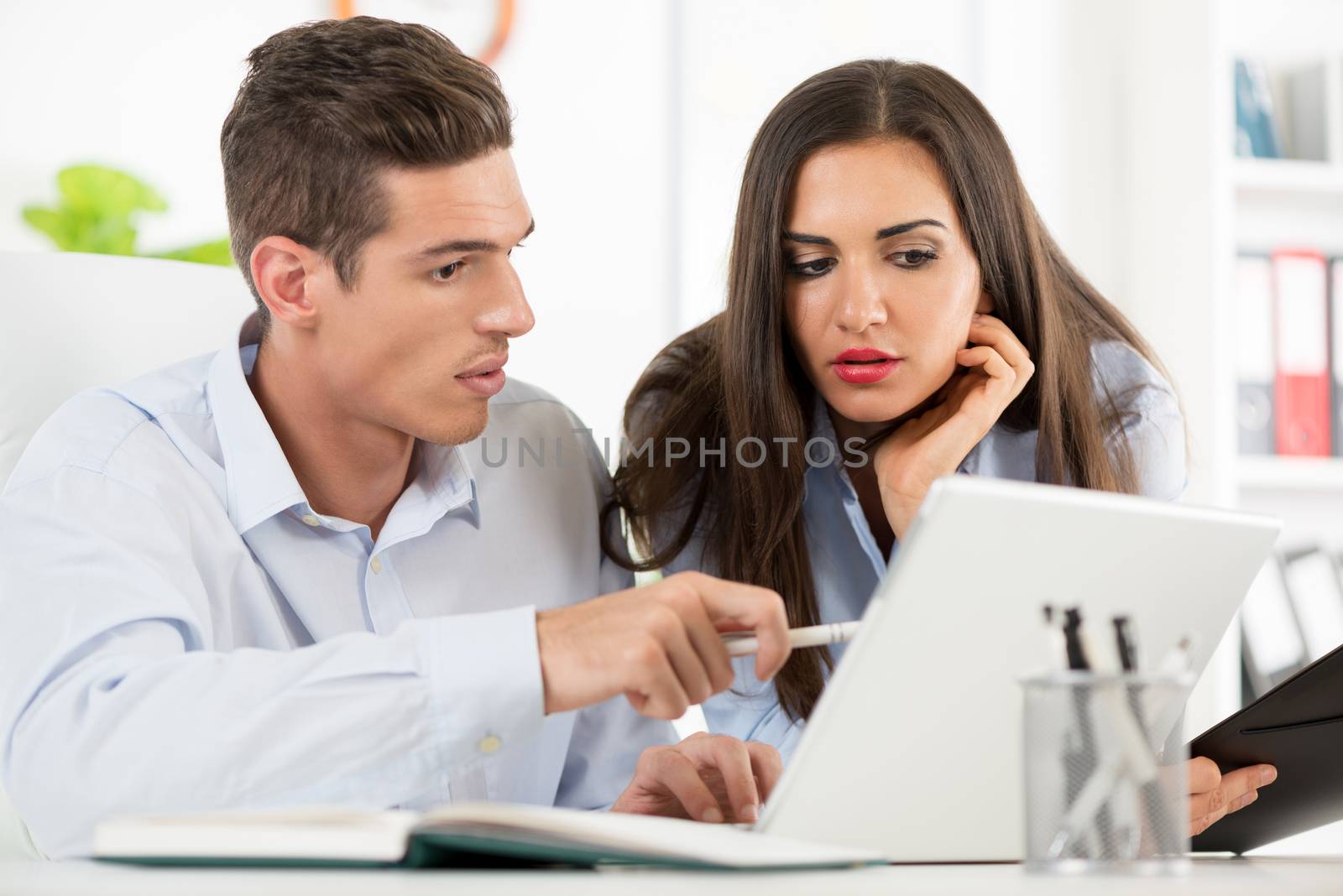 Young beautiful businesswoman and businessman working on laptop in the office.