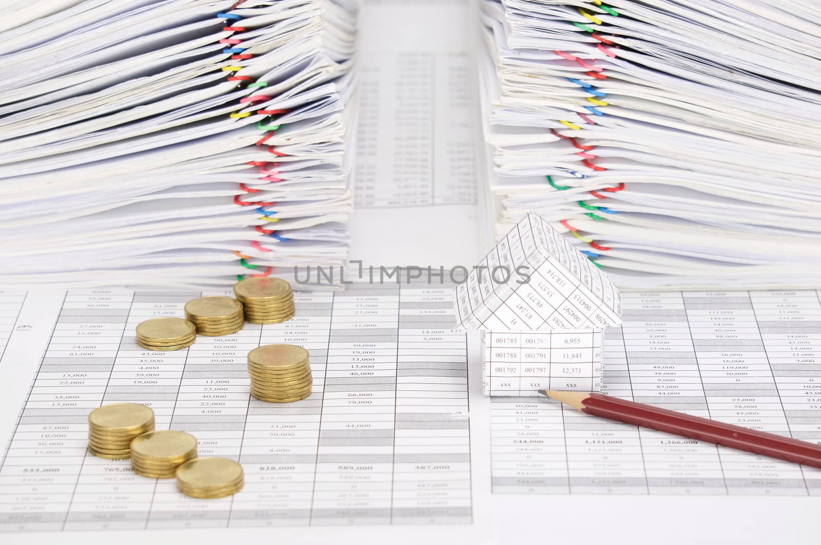 House and pencil with step pile of gold coins on finance account have dual pile overload document of report with colorful paperclip as background.