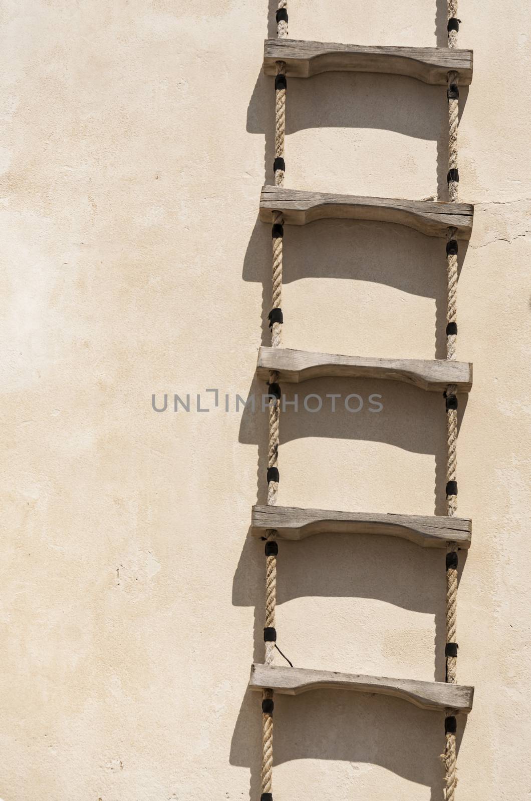 Ladder with rope hanged on a wall