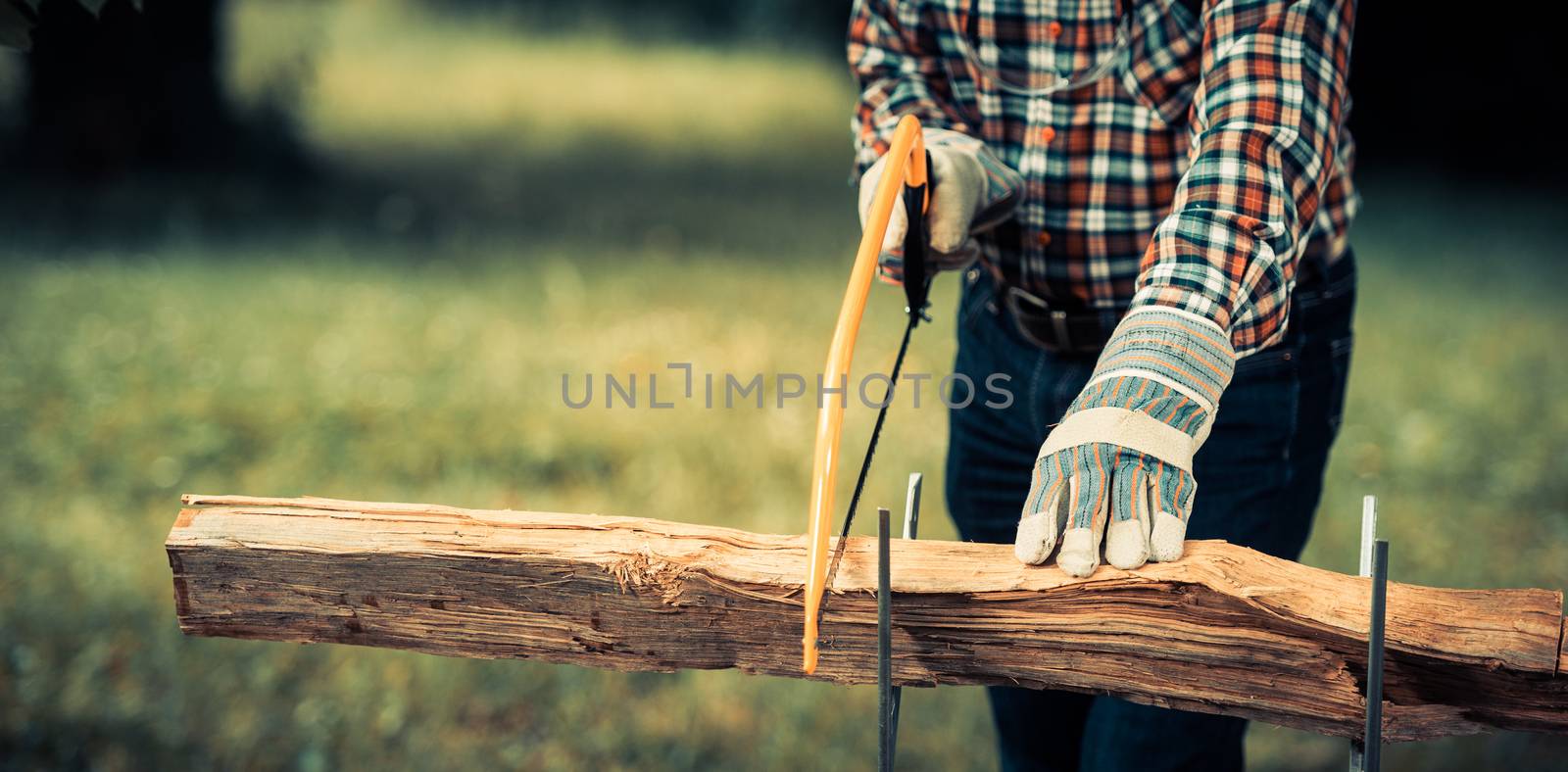 Senior man sawing a log handsaw closeup