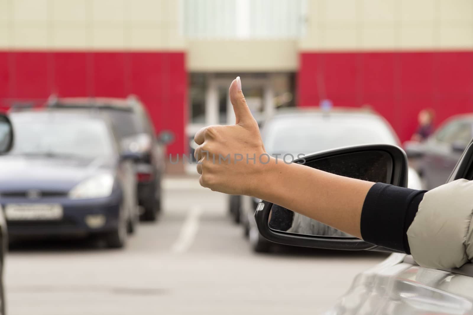 girl makes a gesture with his hand out the window of a passenger car white