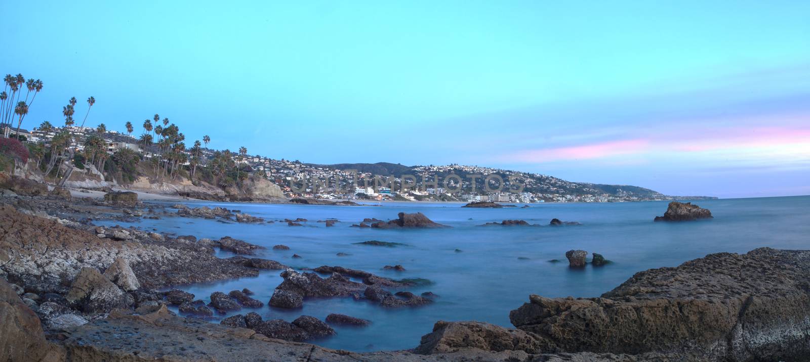 Long exposure of sunset over rocks, giving a mist like effect over ocean in Laguna Beach, California, United States