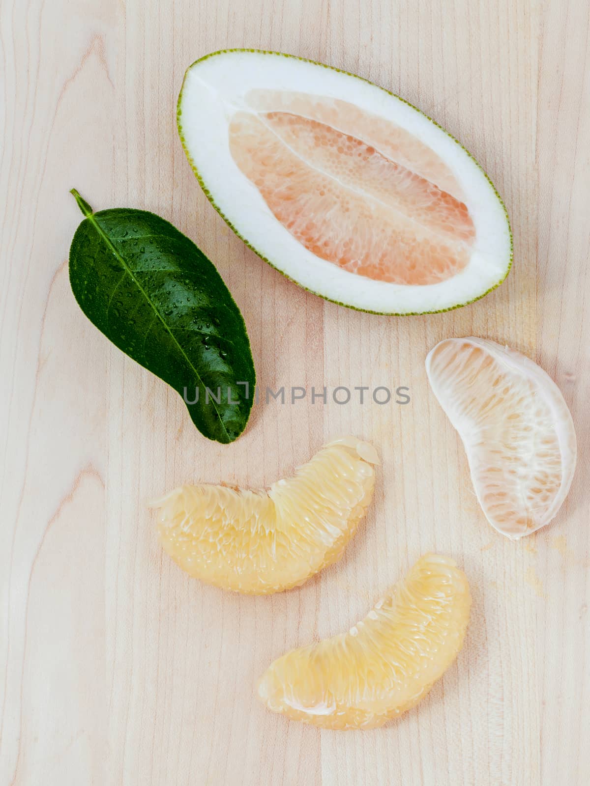 Fresh pomelo cutting and peeled on the wooden background. by kerdkanno