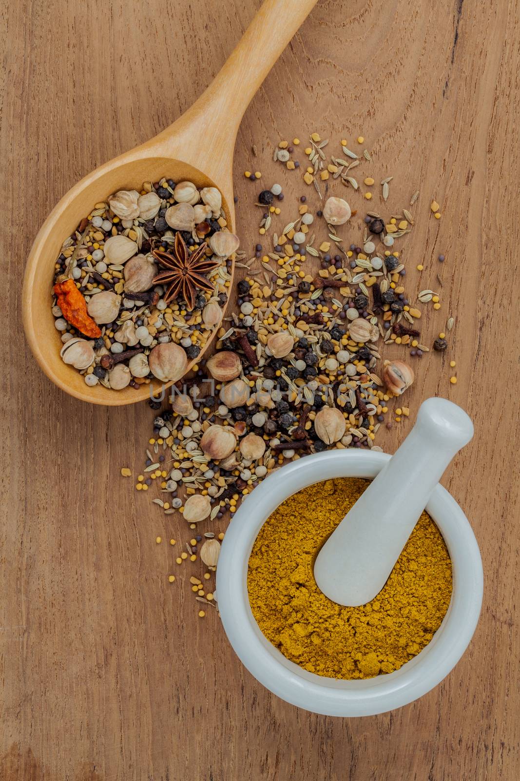 Assorted of spices  in wooden spoon  black pepper ,white pepper, black mustard,yellow mustard,fenugreek,cumin ,curry powder ,paprika and  fennel seeds on teak wood background.