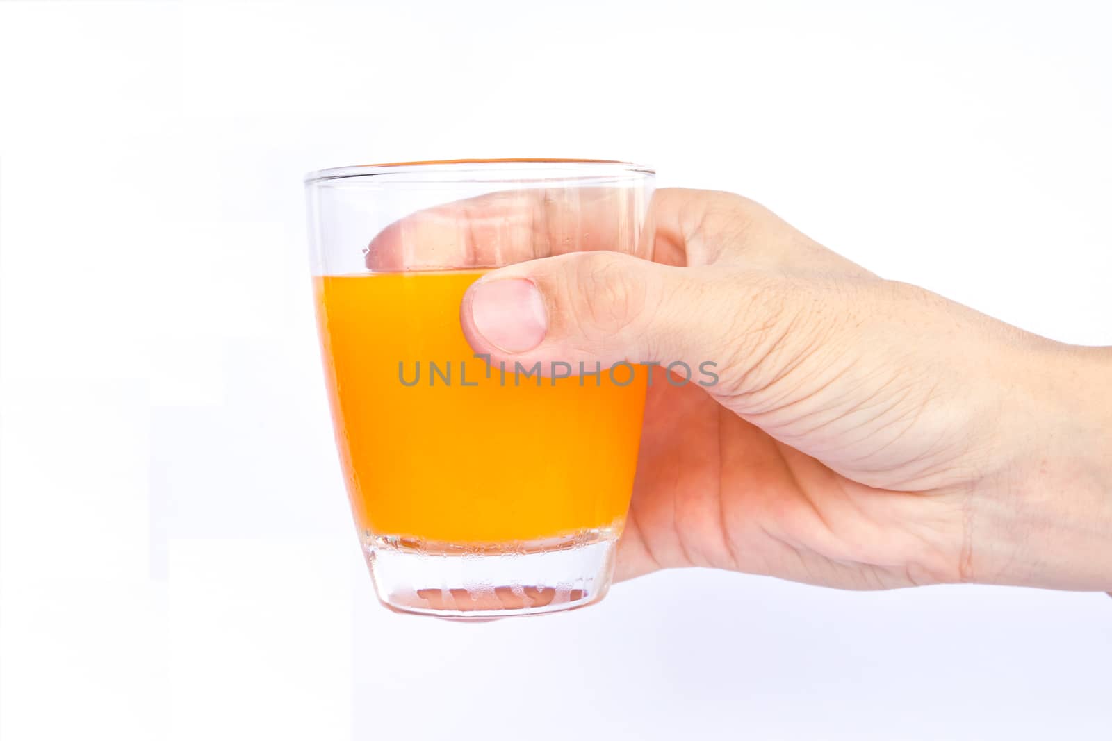 Male hand holding an orange juice glass. 