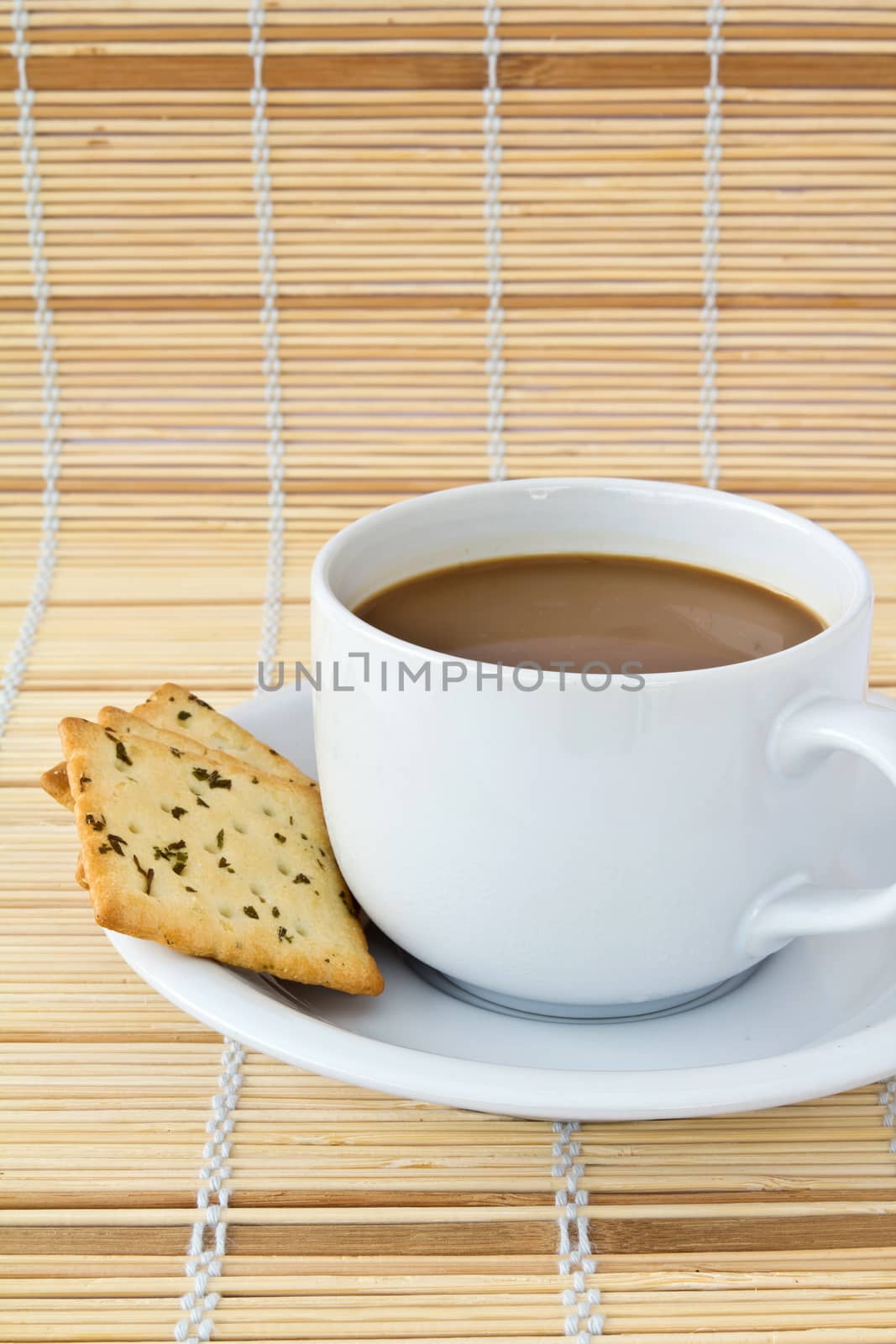 Coffee. White porcelain cup and three biscuit on a mat 