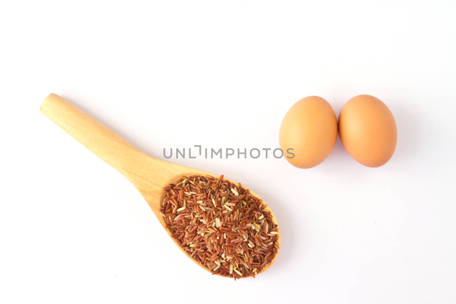 Brown egg and wooden spoon with red rice; on a white background