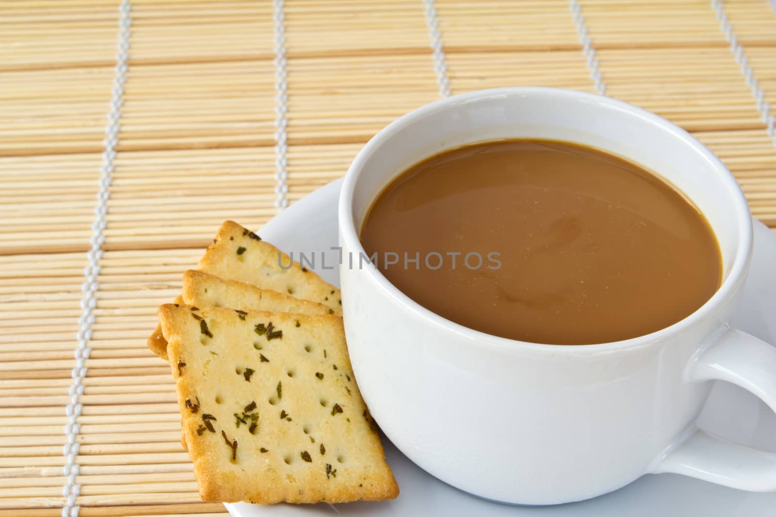 Coffee. White porcelain cup and three biscuit on a mat 