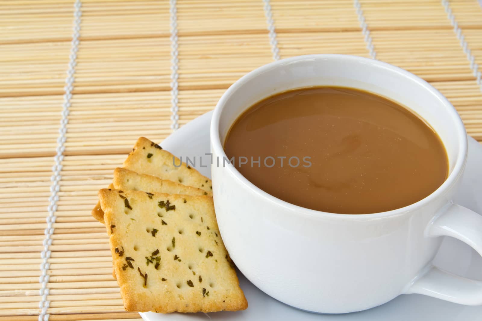 Coffee. White porcelain cup and three biscuit on a mat 