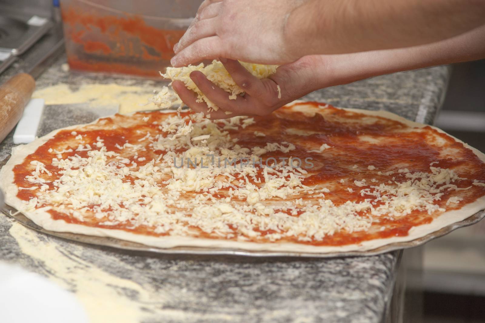 Man chef with raw pizza. Young male in uniform preparing pizza on table.