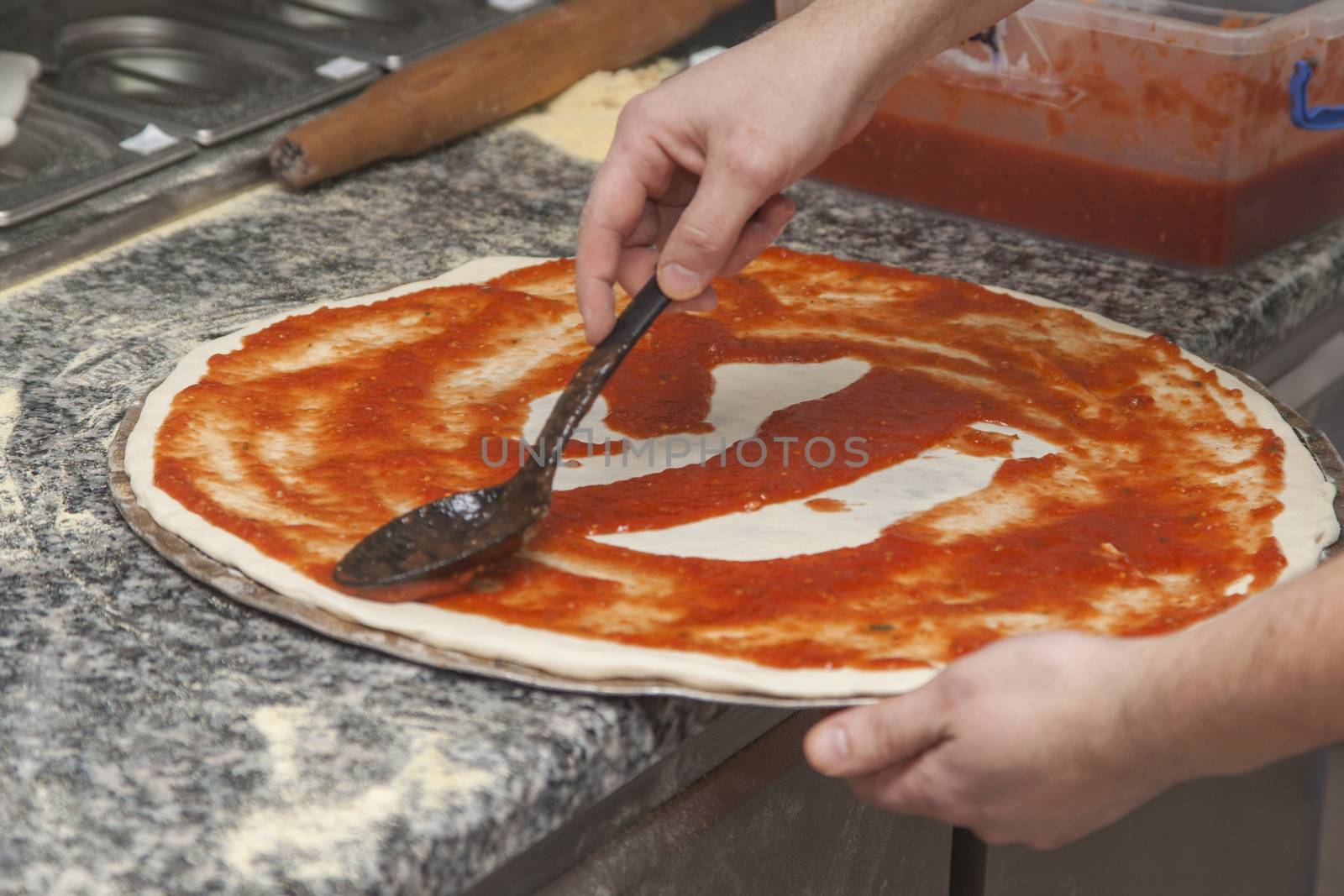 Man chef with raw pizza. Young male in uniform preparing pizza on table.