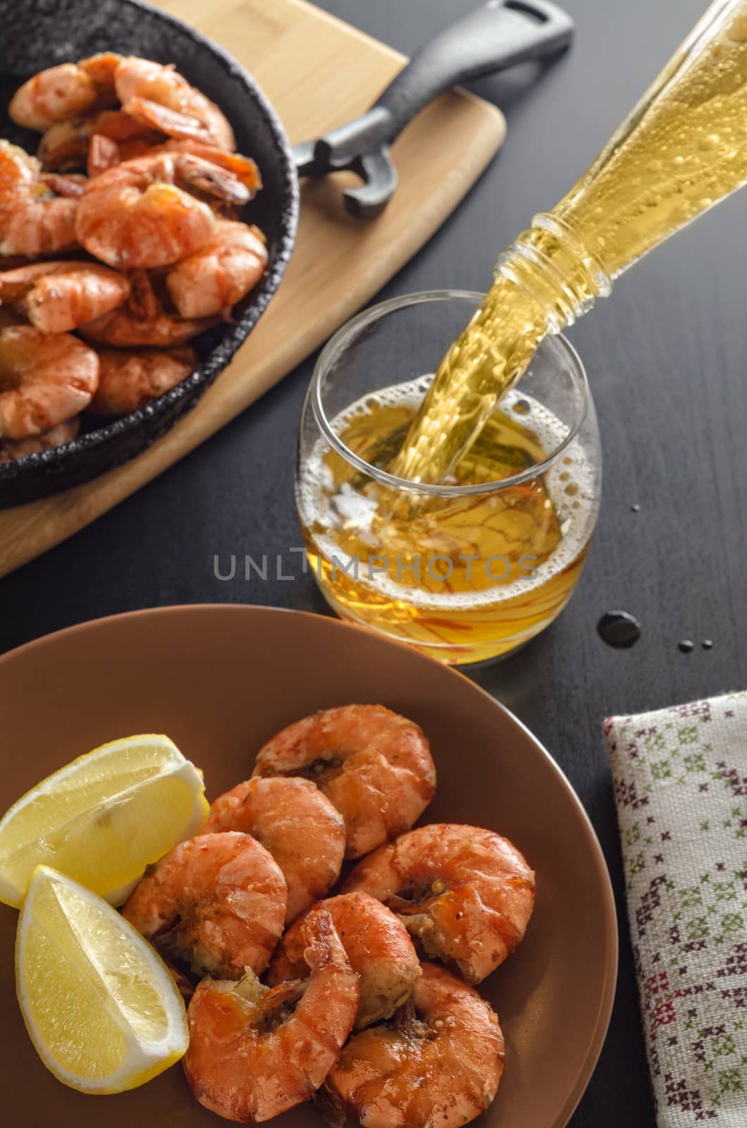 Fried shrimp on a platter, in the background filled with beer and a frying pan with shrimp.