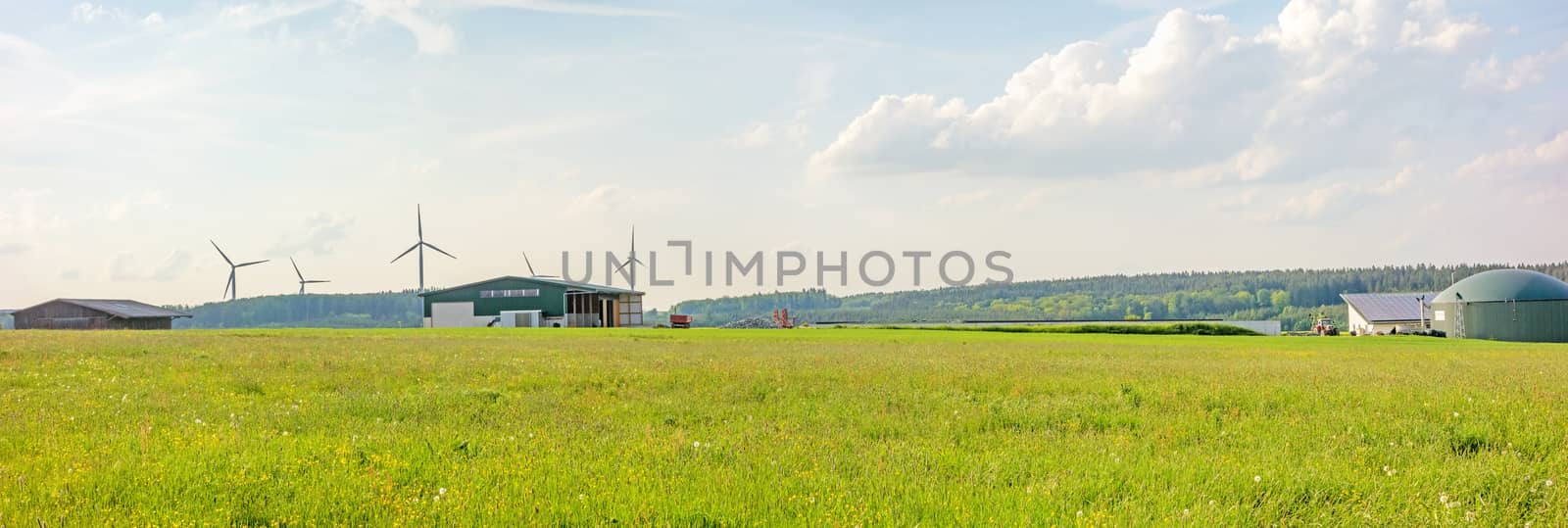 Farm with barn and biogas plant, green meadow in front