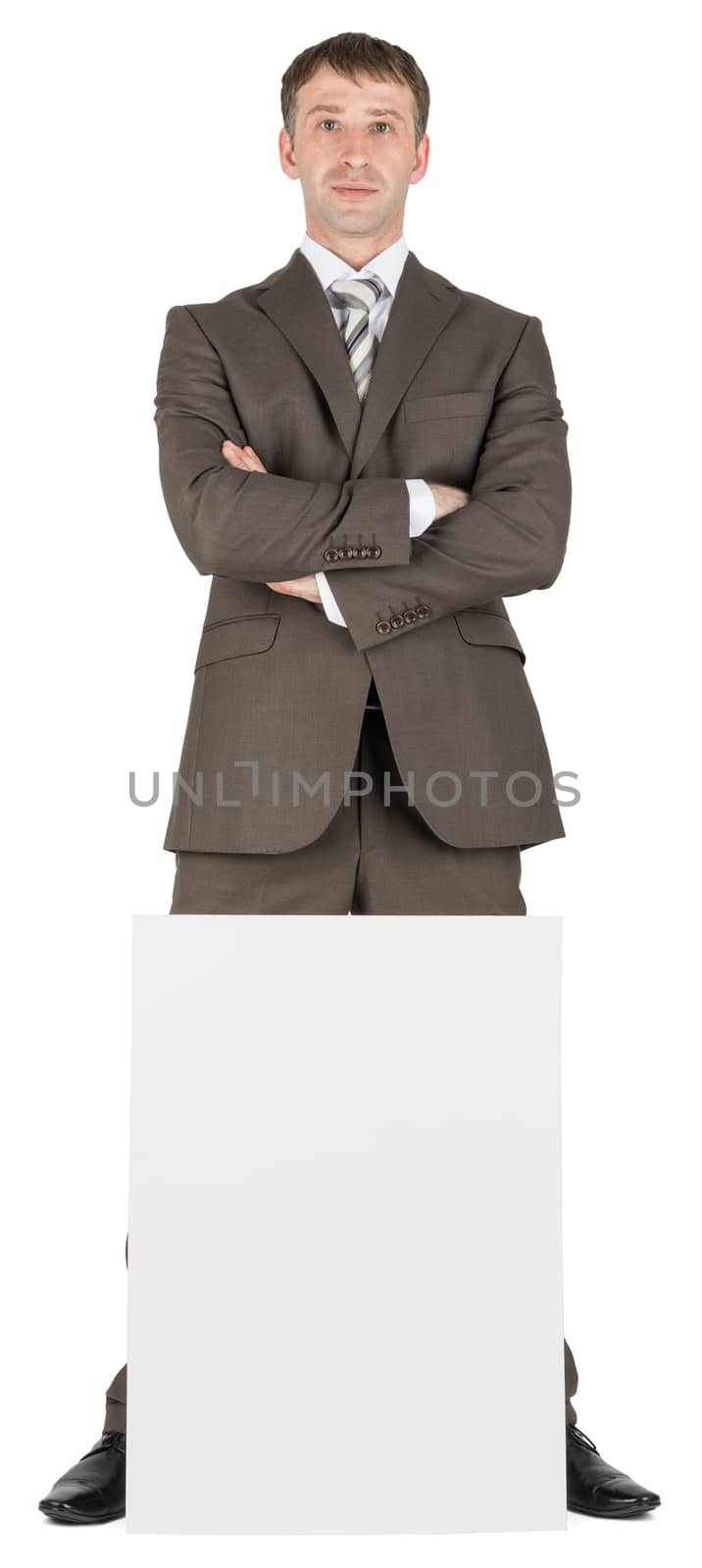Businessman with crossed arms behind blank paper isolated on white background