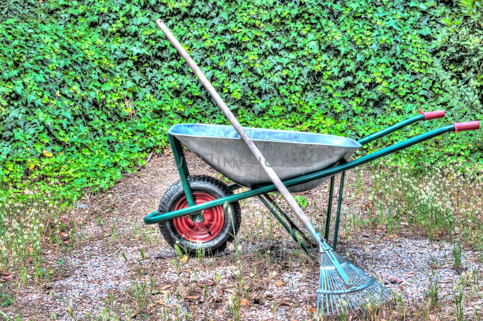 hdr of wheelbarrow in a garden and a rake