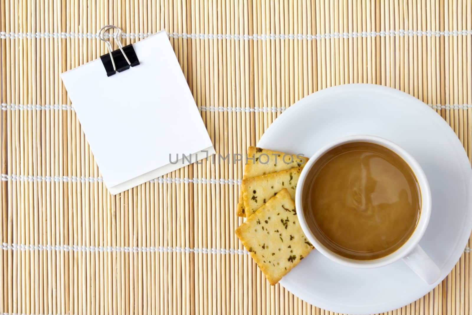 White cup of hot coffee and white sketch book on a mat 