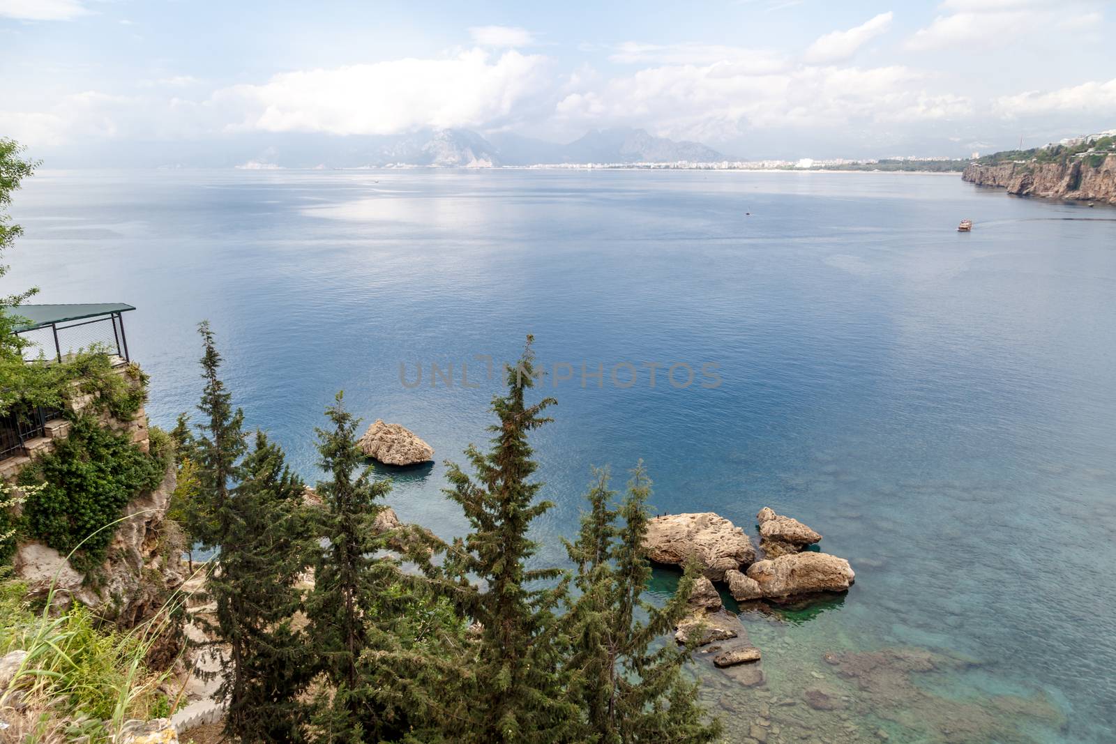 Seascape view of Antalya with beautiful mediterranean sea and green trees around, on cloudy sky background.