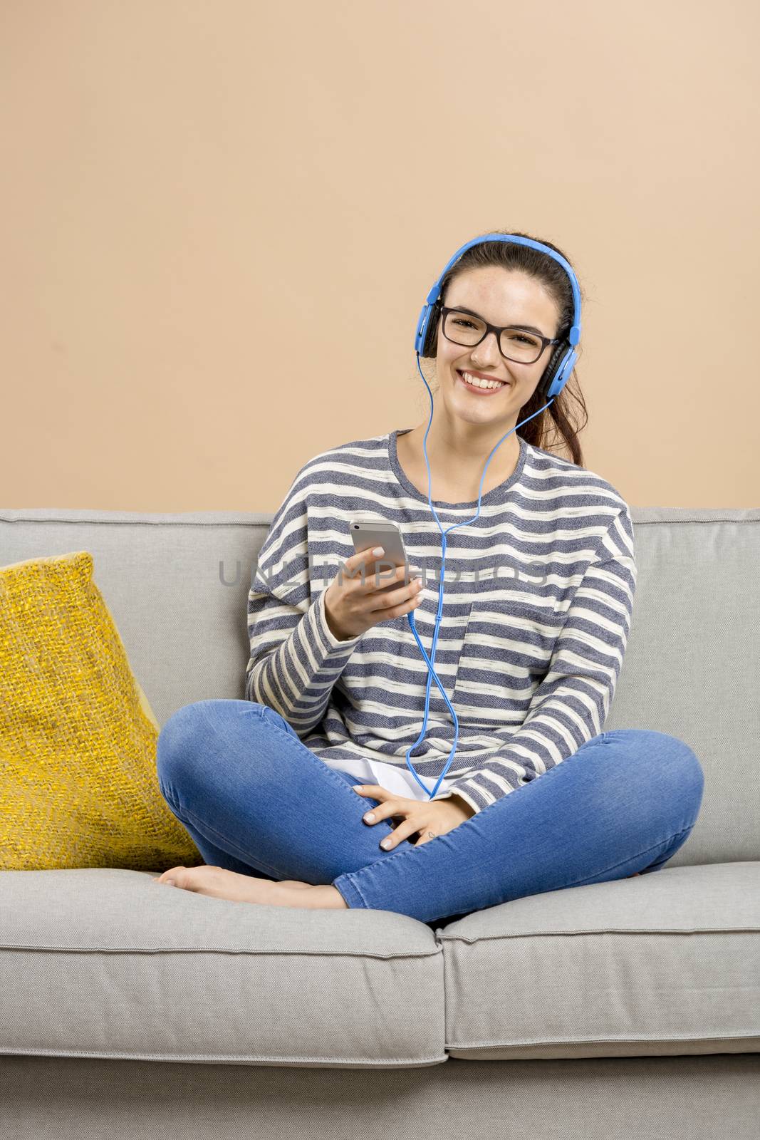 Beautiful woman at home sitting on the sofa and listen music