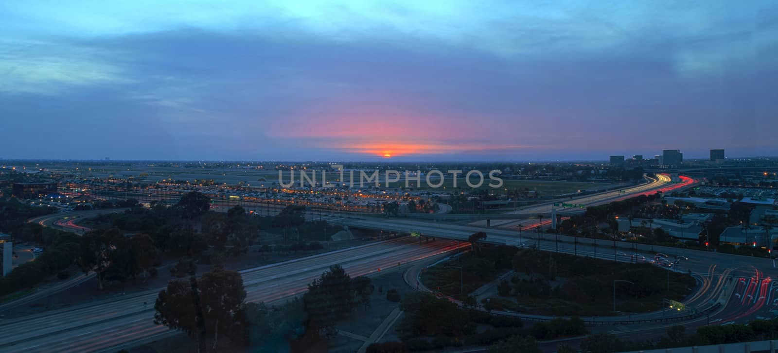 Irvine, California, February 26, 2016: Aerial view of John Wayne Airport in Orange County, California, at sunrise with light trails across the 405 highway in front.