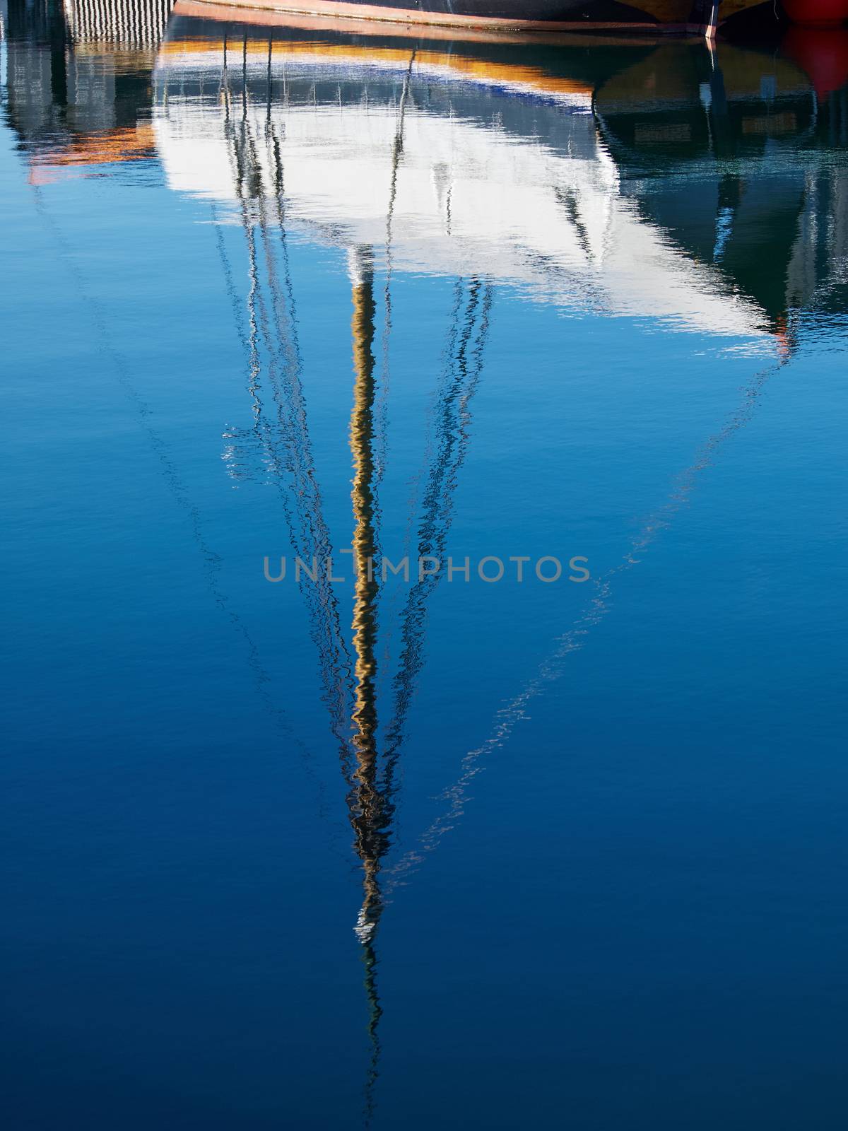 Reflection of a sailing yacht in the sea water of a marina