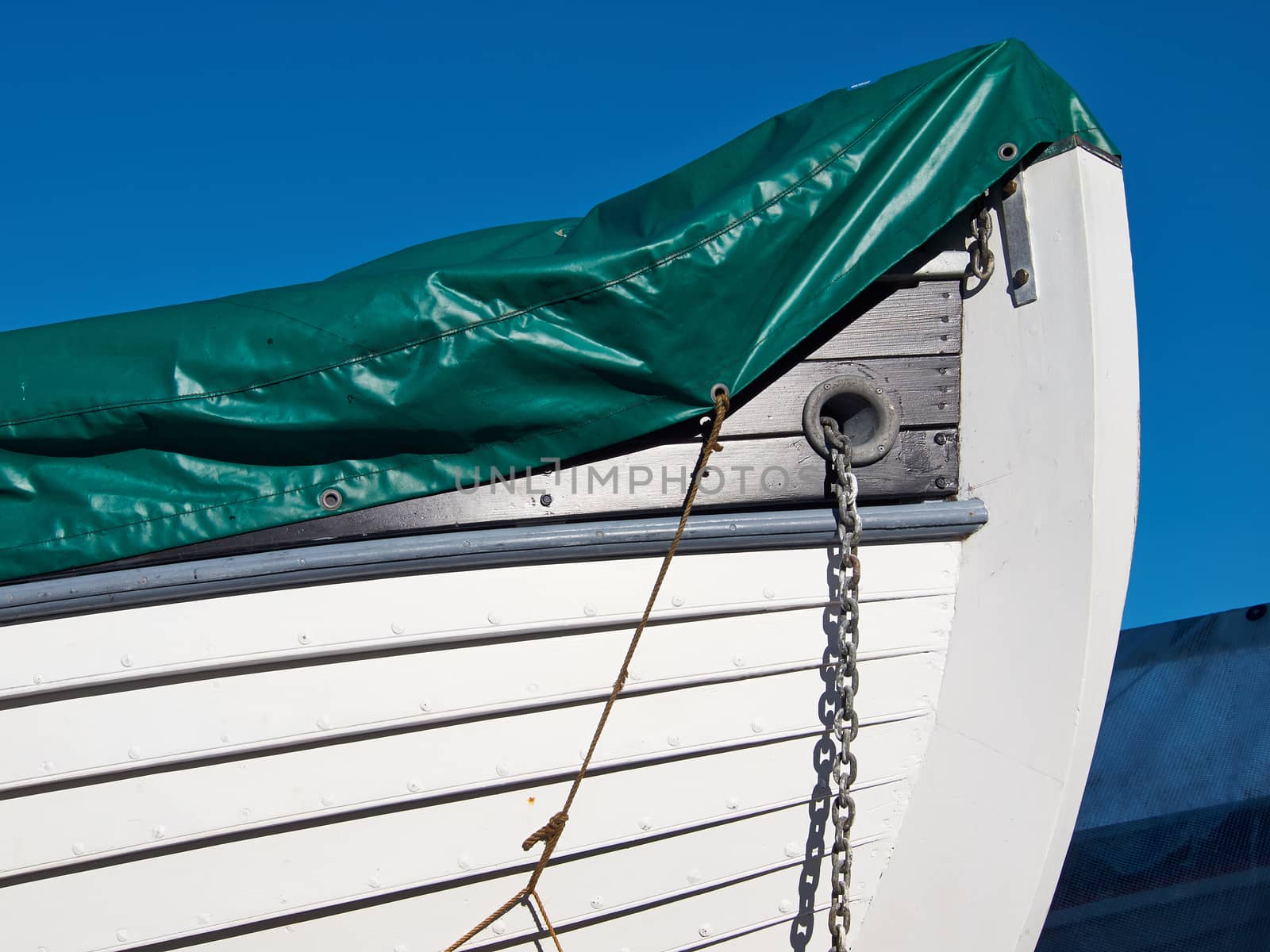 Prow of a small white wooden boat with clear blue sky background      