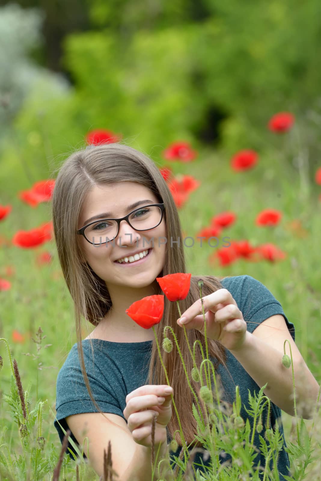 Portrait of young girl with poppy flowers in nature