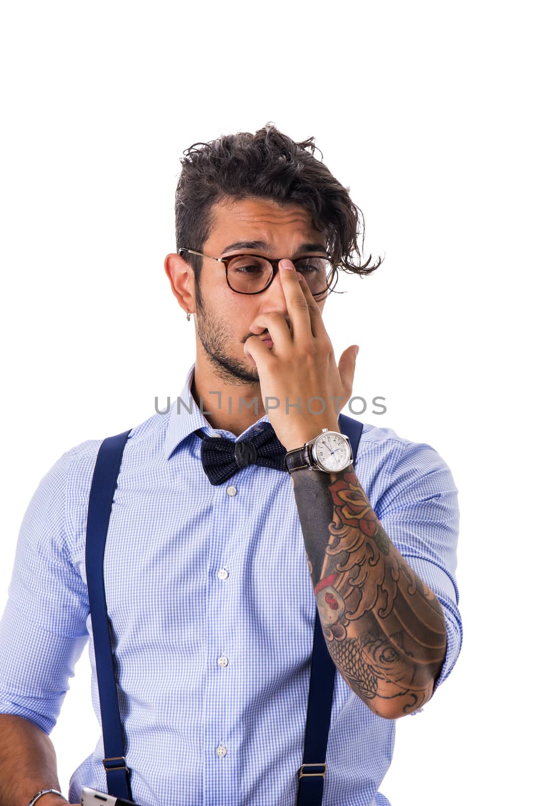 Portrait of shy or embarassed young man in glasses,bow-tie,suspenders and shirt looking away. Studio shot