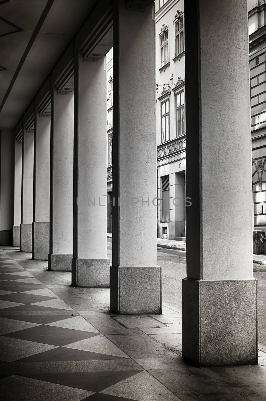 Symmetrical corridor of pillars next to a street.