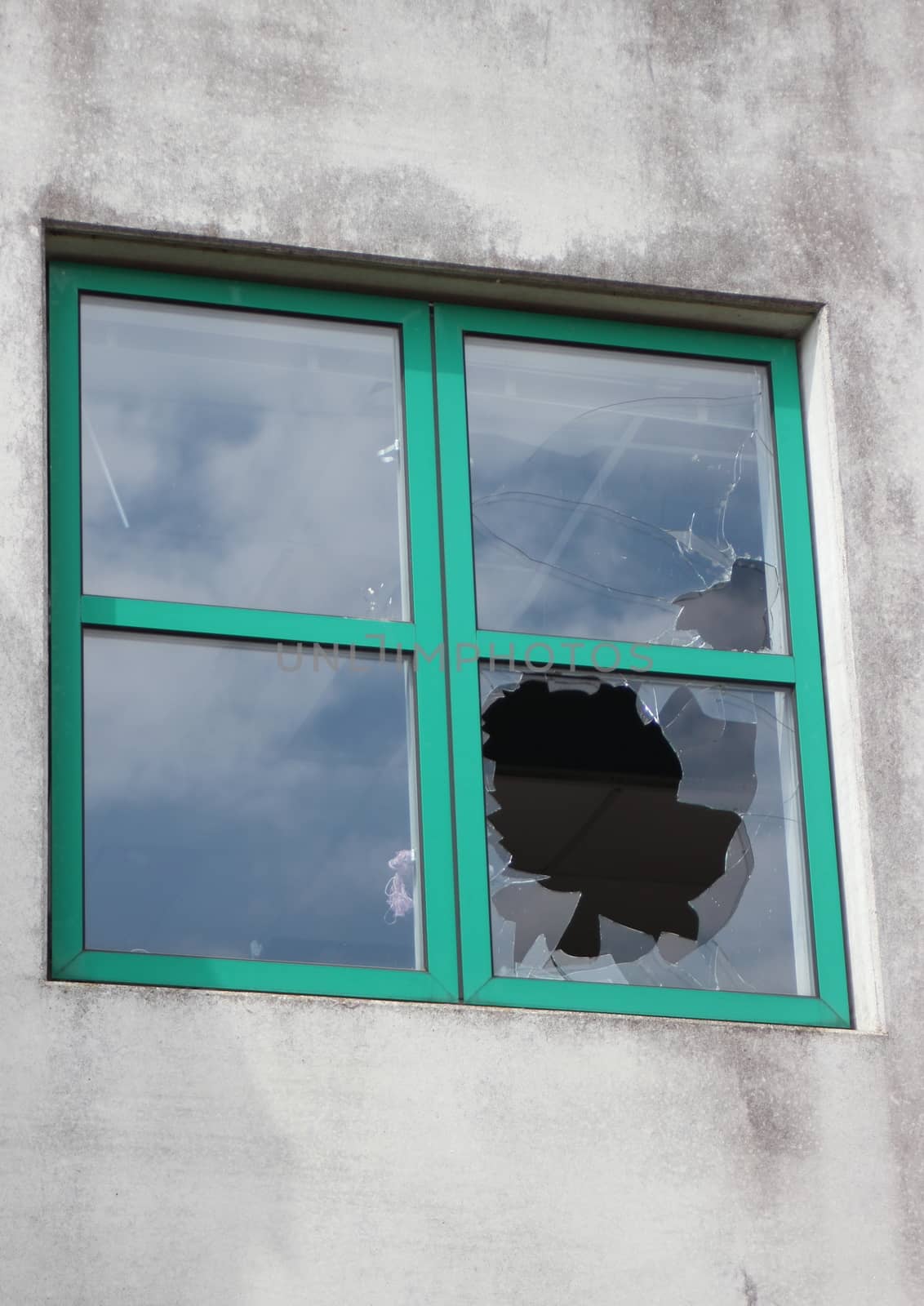 Broken glass in window with green frame at  factory by HoleInTheBox