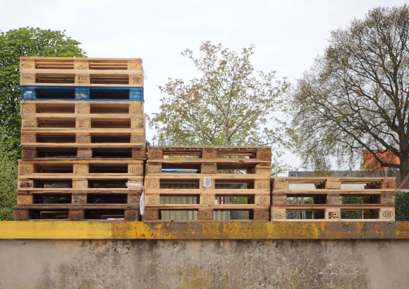 Three piles of wodden Europe pallets with one in color by HoleInTheBox