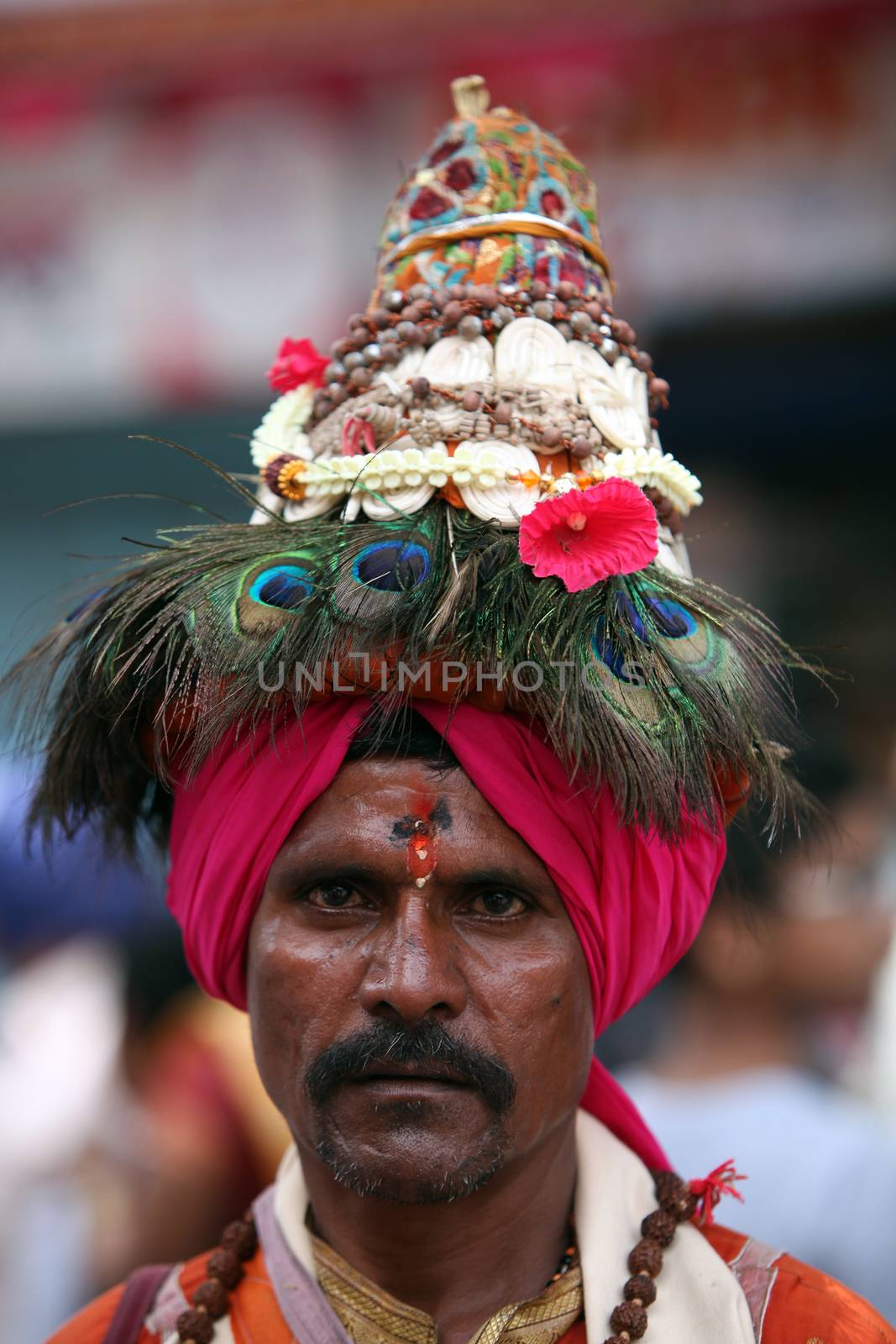 Pune, India - July 11, 2015: A portrait of a Vasudev, pilgrims who are devotees of Lord Vishnu and wear a conical hat with peacock feathers. Vasudev has been a traditional since many years in Maharashtra. THese pilgrims go around singing praises of Lord Vishnu.